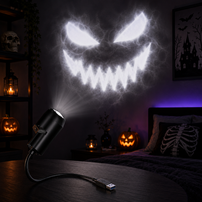 A black USB projecting light on a dark wooden table projects a large glowing white spooky face onto a wall in a dimly lit bedroom with Halloween decorations, including jack-o'-lanterns, candles, and a skeleton pillow.