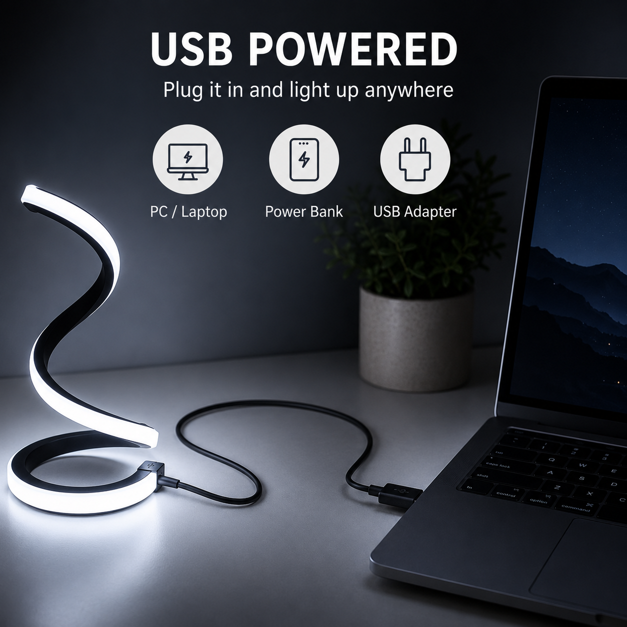 A curved USB-powered LED desk lamp with a white illuminated light bar and black cord, shown plugged into a laptop on a desk with a small plant in the background. Text at the top reads 'USB POWERED' with icons for PC/Laptop, Power Bank, and USB Adapter.